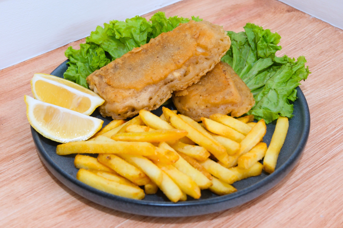 Crispy Fish and Chips on a plate, served with golden fries, fresh lettuce, and lemon slices, with a side of tartar sauce.