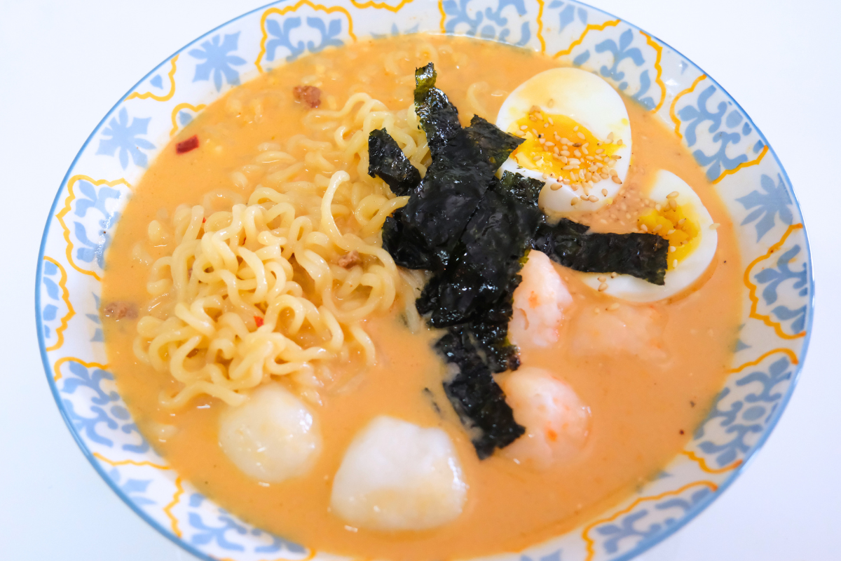 A bowl of creamy instant ramen topped with Fishta Hotpot Scallop & Shrimp Balls, nori, and a rich, flavorful broth.