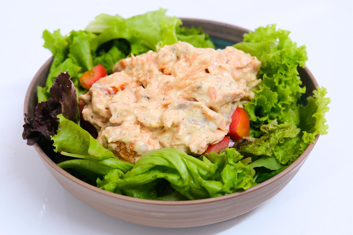 A bowl of Salmon Salad with Creamy Herb Dressing, featuring Fishta Salmon, fresh lettuce, cherry tomatoes, and a creamy, herb-infused dressing.